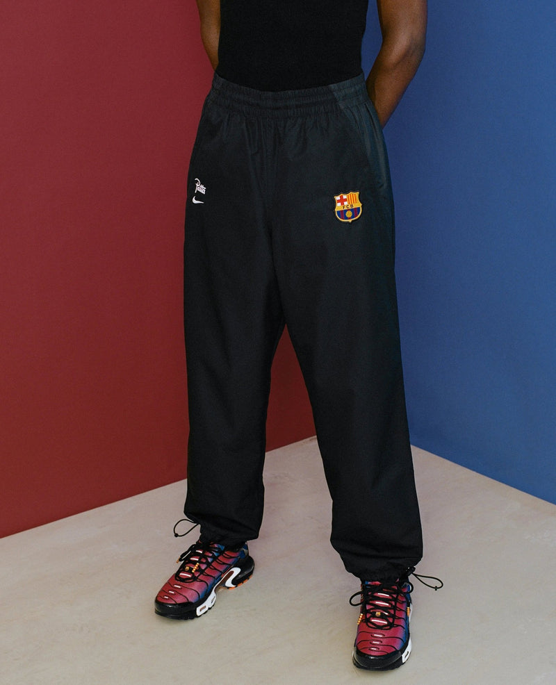 Model wearing black FCB x Patta Culers del Món track pants featuring FC Barcelona badge and embroidered logos.