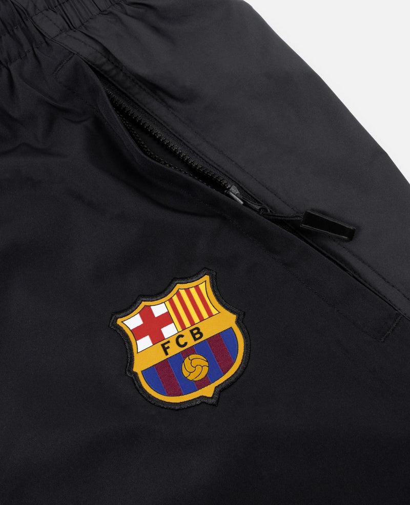 Close-up of FC Barcelona crest badge and zippered pocket on black FCB x Patta track pants.
