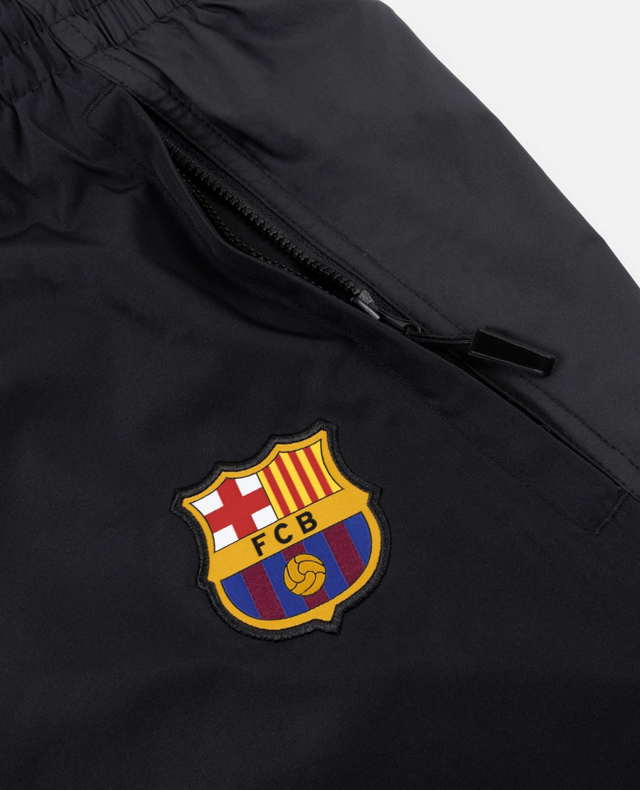 Close-up of FC Barcelona crest badge and zippered pocket on black FCB x Patta track pants.