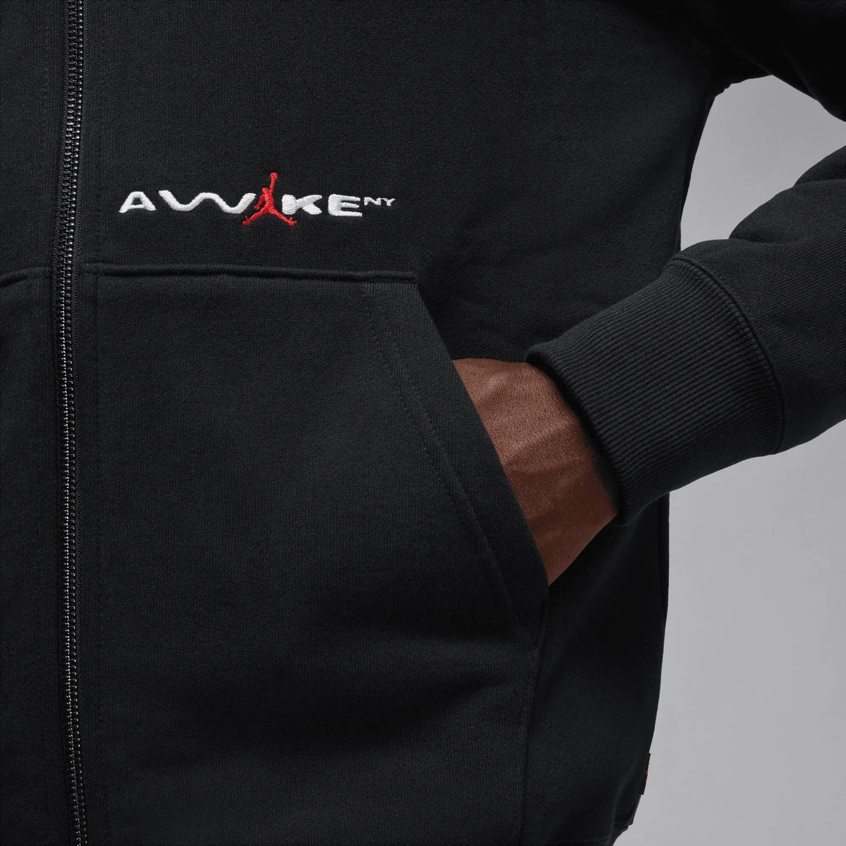 Close-up of the black Jordan x Awake NY full-zip fleece hoodie with embroidered chest logo and pocket.