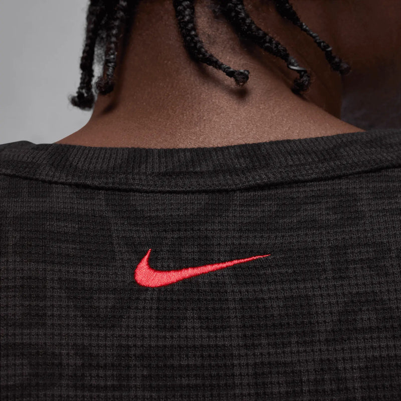 Close-up back view of the Jordan x Awake NY black thermal shirt showing an embroidered red Nike Swoosh.