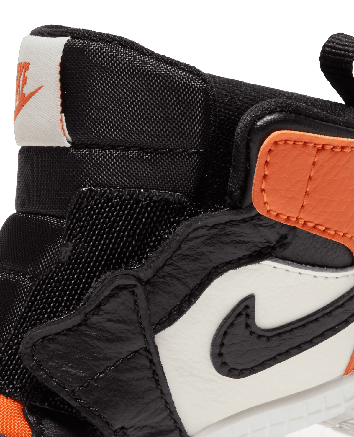 Detail of the Nike Jordan 1 Crib Bootie ankle collar in Sail, Black, and Starfish orange leather.