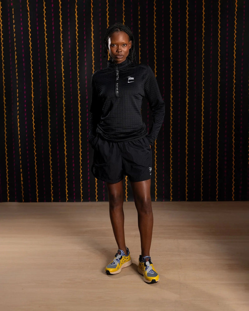 Model wearing the Nike x Patta Running Team black half-zip longsleeve with matching shorts.
