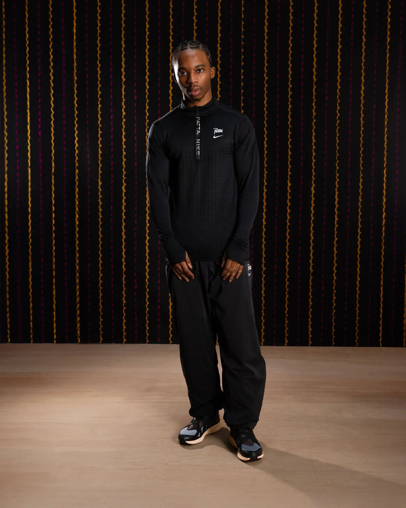 Nike x Patta Running Team black half-zip longsleeve worn by a male model with black pants.