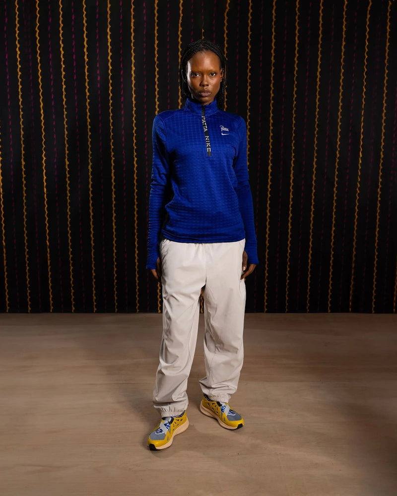 Female model wearing the Nike x Patta Running Team deep royal blue half-zip longsleeve top.