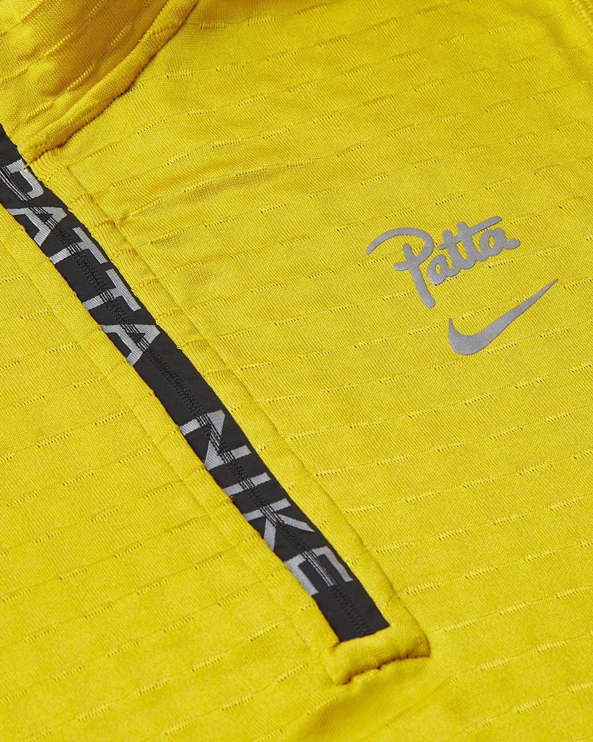 Close-up of the saffron yellow Nike x Patta half-zip top featuring a branded zipper and reflective chest logo.