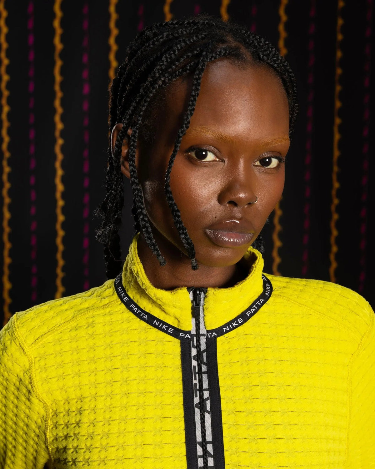 Close-up of a model wearing the Nike x Patta Running Team half-zip longsleeve in saffron quartz yellow.