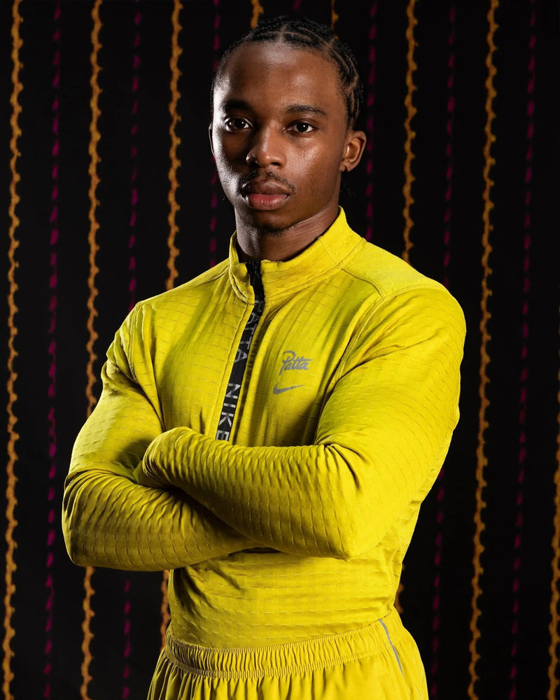 Model wearing the saffron yellow Nike x Patta Running Team half-zip longsleeve top.
