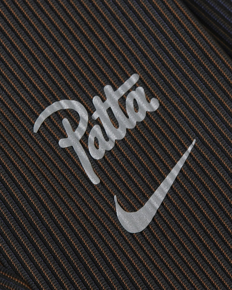 Close-up of the reflective Nike x Patta logo on black ribbed leggings.