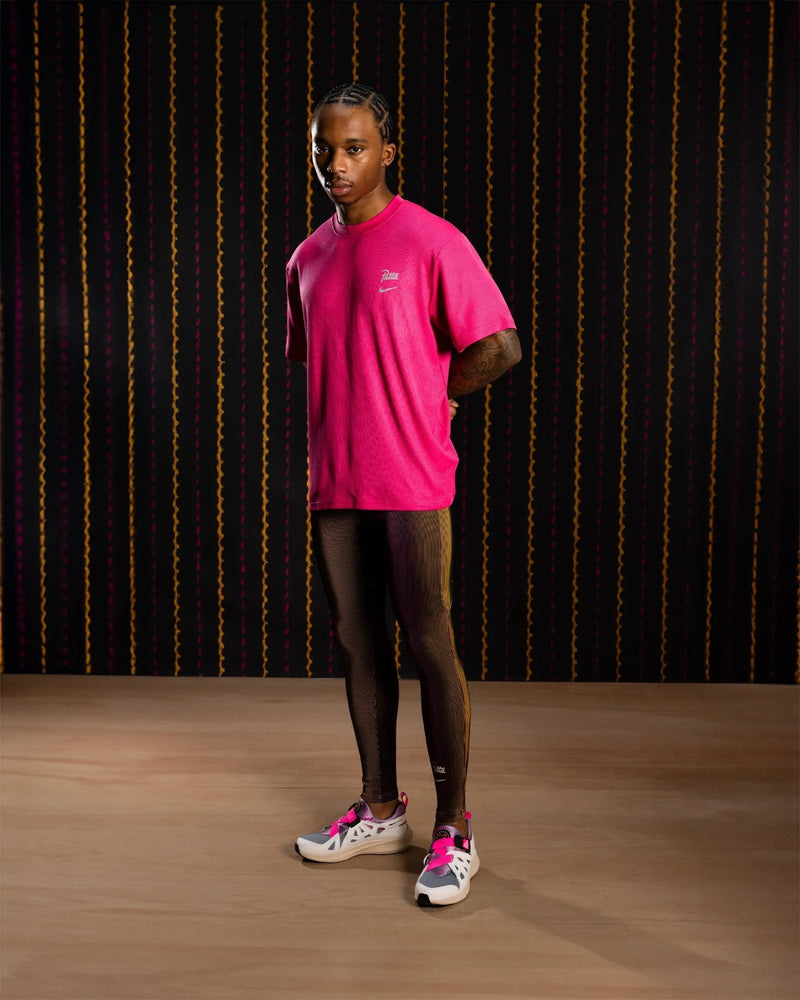 Nike x Patta Running Team leggings in Fireberry and Sundial worn by a male model.