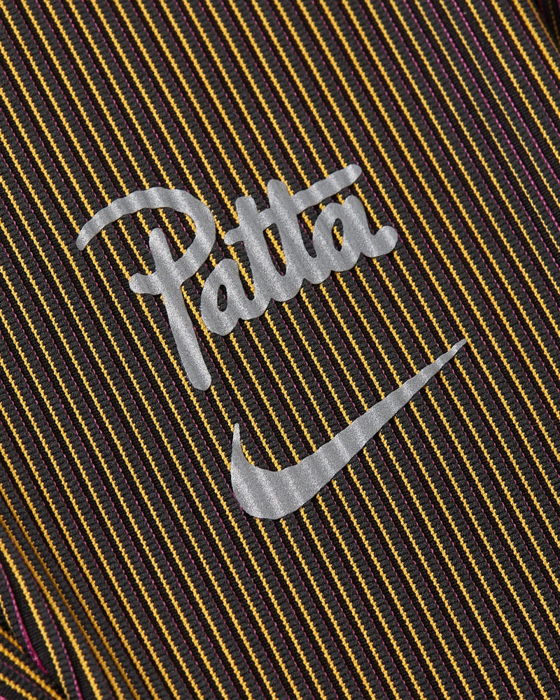 Close-up of reflective Patta script and Nike Swoosh on Fireberry and Sundial ribbed running leggings.