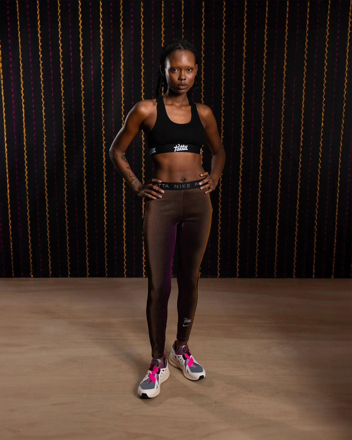 Model wearing iridescent Nike x Patta Running Team leggings in Fireberry and Sundial.