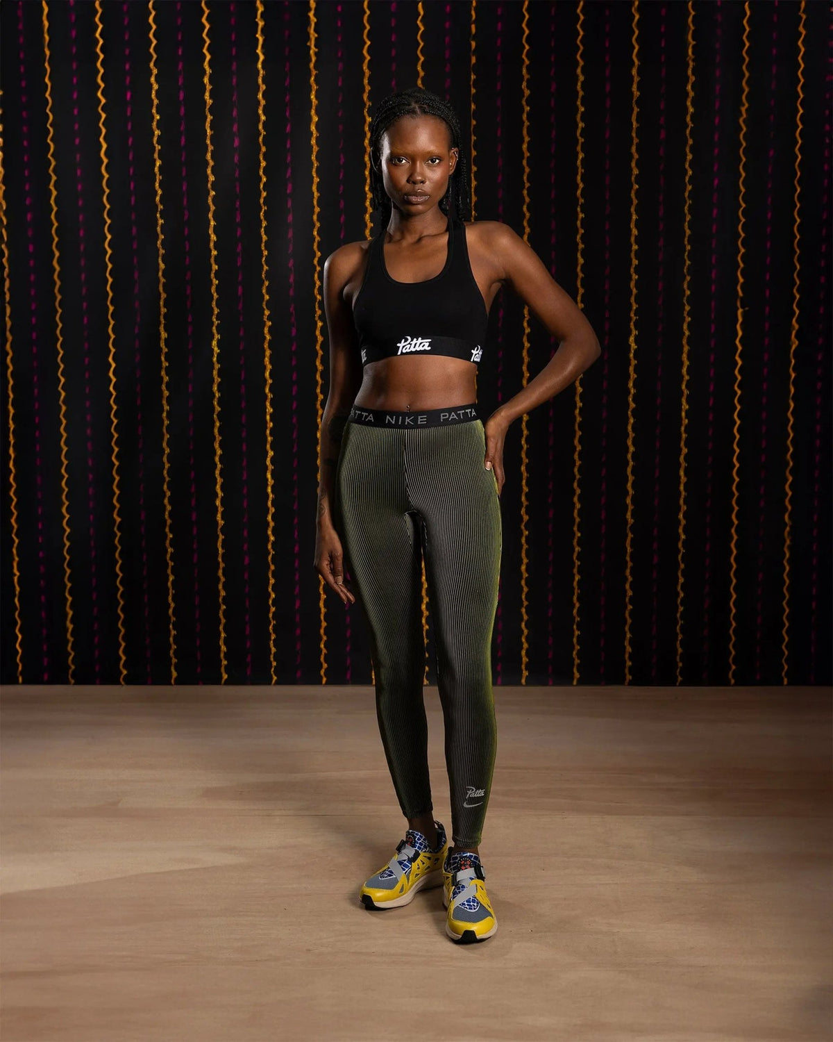 Full-length shot of a model wearing Nike x Patta Running Team leggings in saffron quartz.