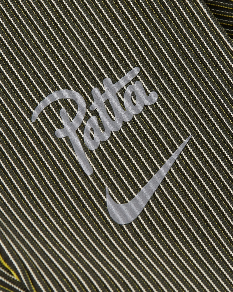 Reflective Nike and Patta script logo on ribbed Saffron Quartz running leggings.