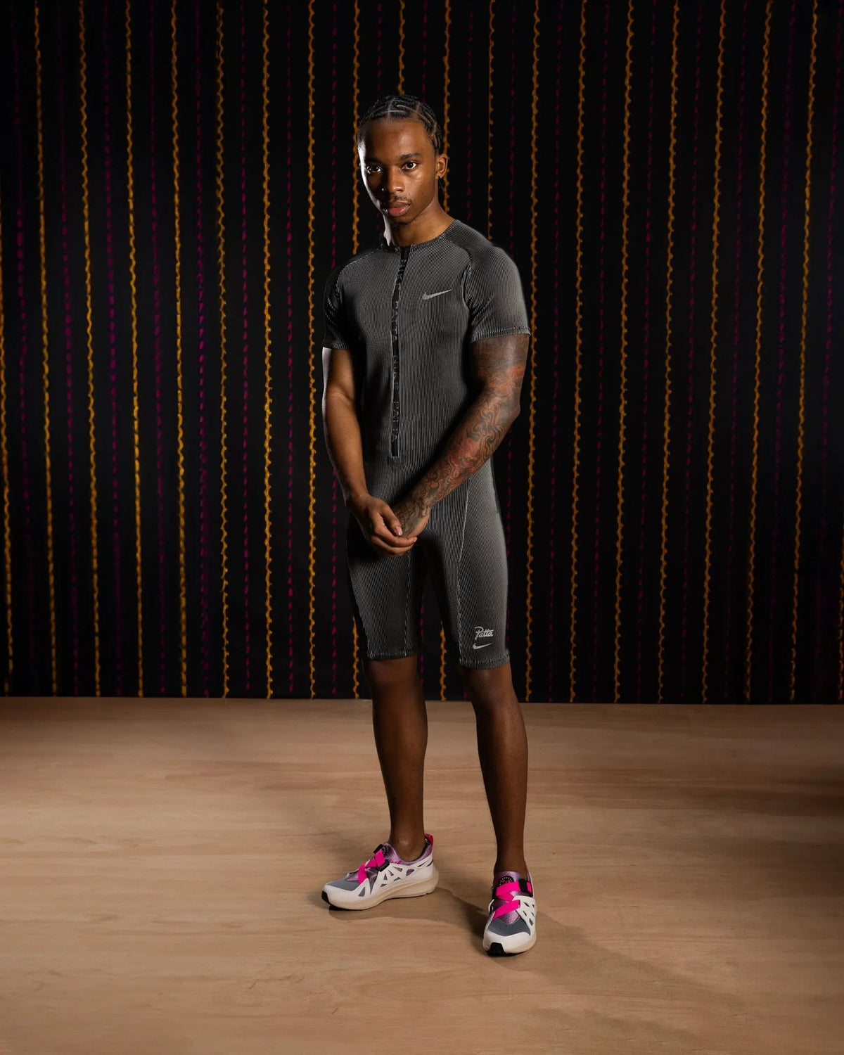 Model wearing the Nike x Patta Running Team race suit in black and grey.