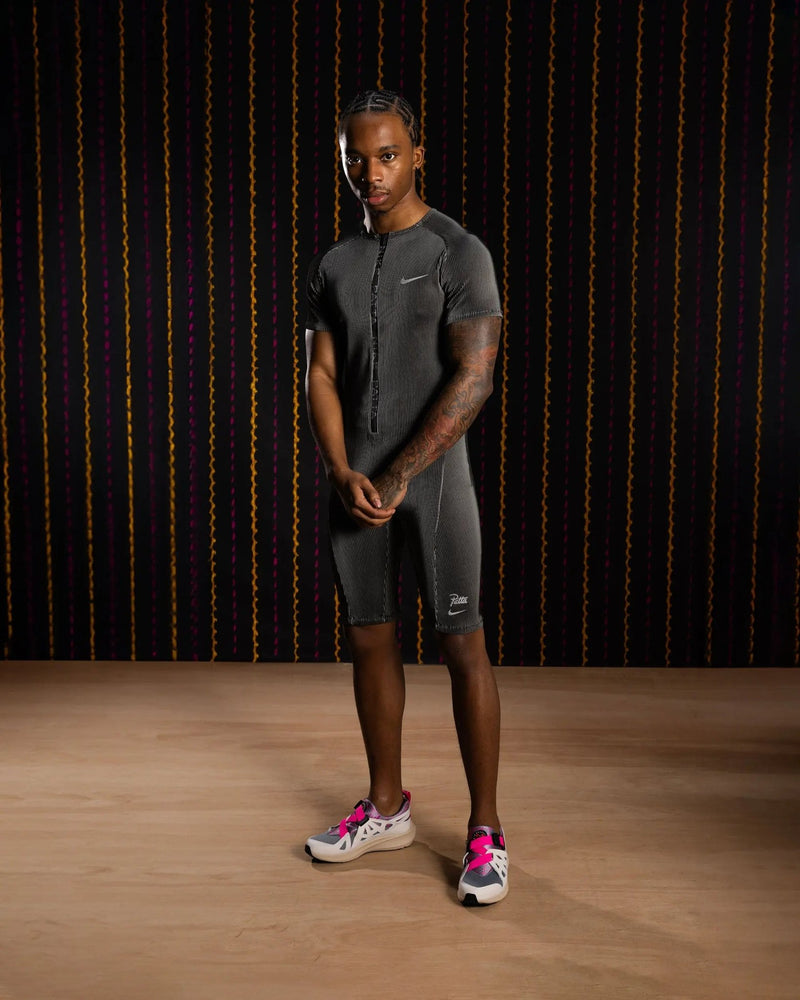 Model wearing the Nike x Patta Running Team race suit in black and grey.