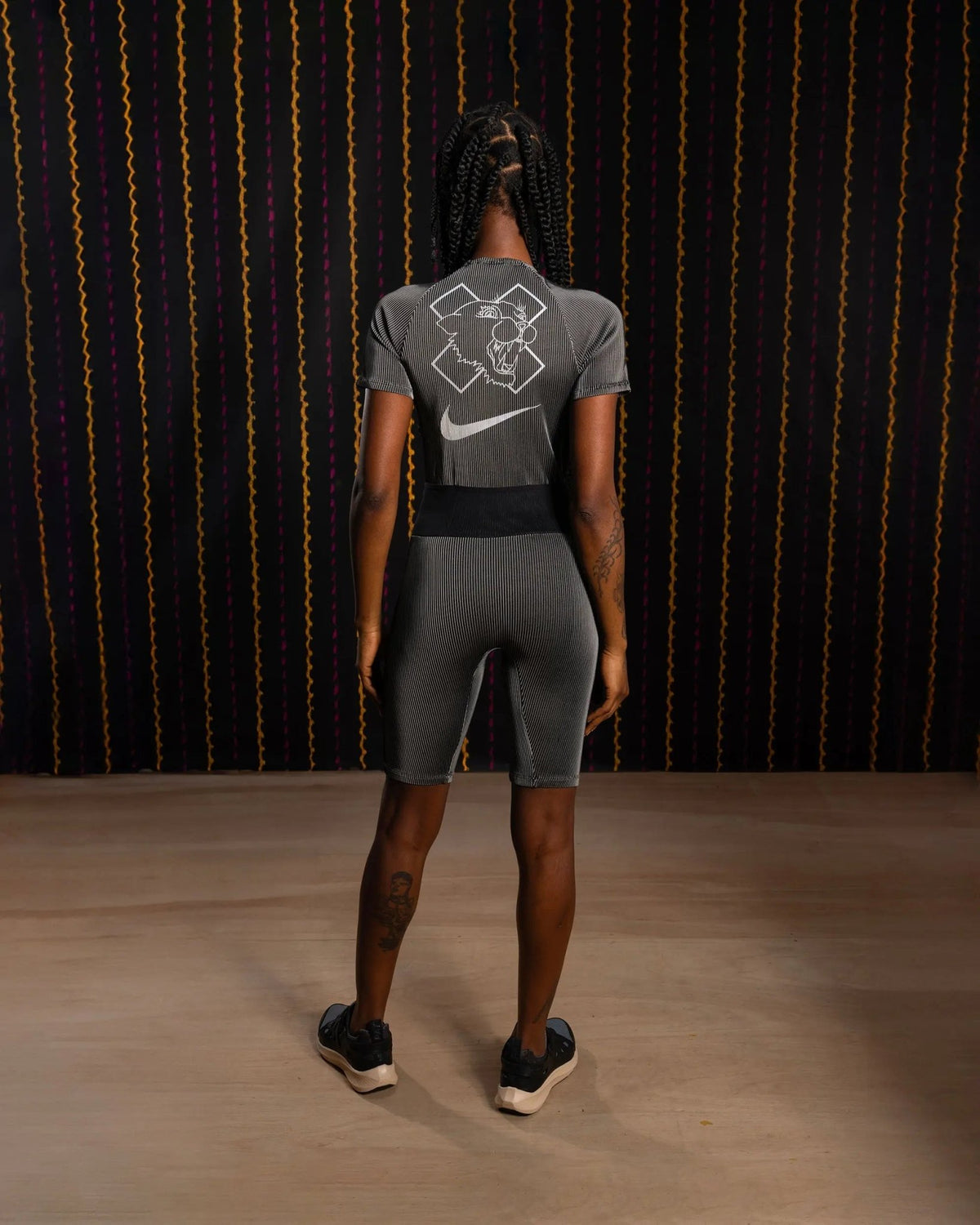 Back view of the black and grey Nike x Patta Running Team Race Suit featuring rear graphics.