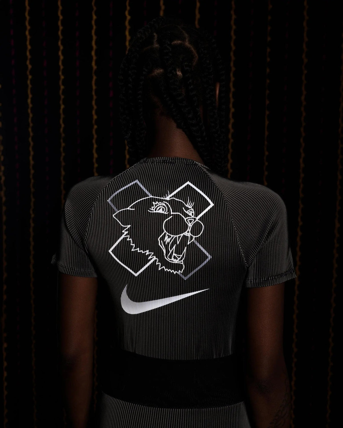 Back view of the Nike x Patta Race Suit in black and grey featuring a reflective panther graphic and Swoosh.
