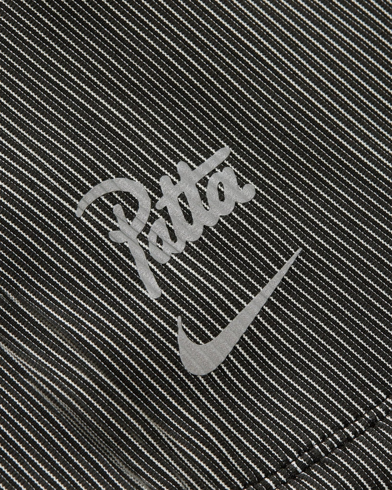 Close-up of the reflective Nike and Patta logos on the black and grey textured Running Team race suit.