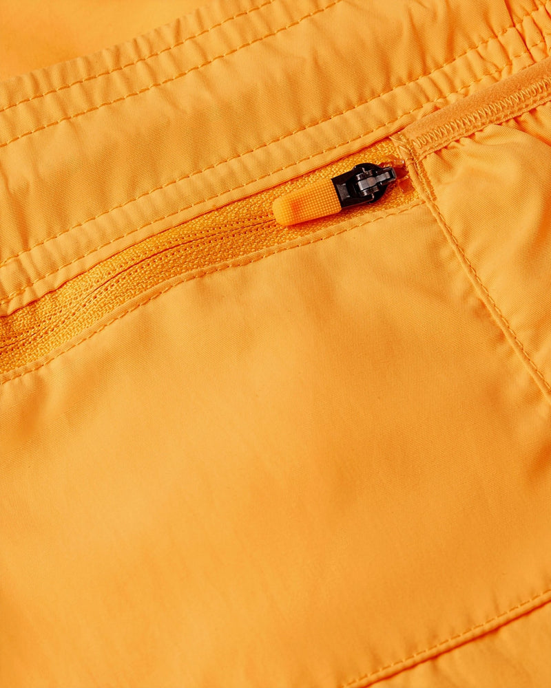 Close-up of the zippered pocket on the Nike x Patta Running Team Shorts in Sundial orange nylon.