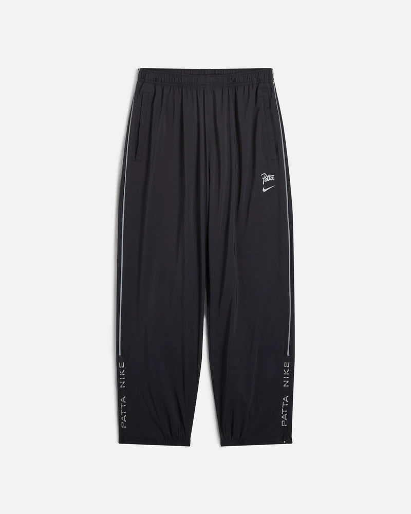 Front view of black Nike x Patta Running Team track pants with reflective side piping.