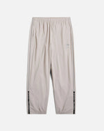 Front view of Nike x Patta Running Team track pants in Sanddrift cream with reflective piping.