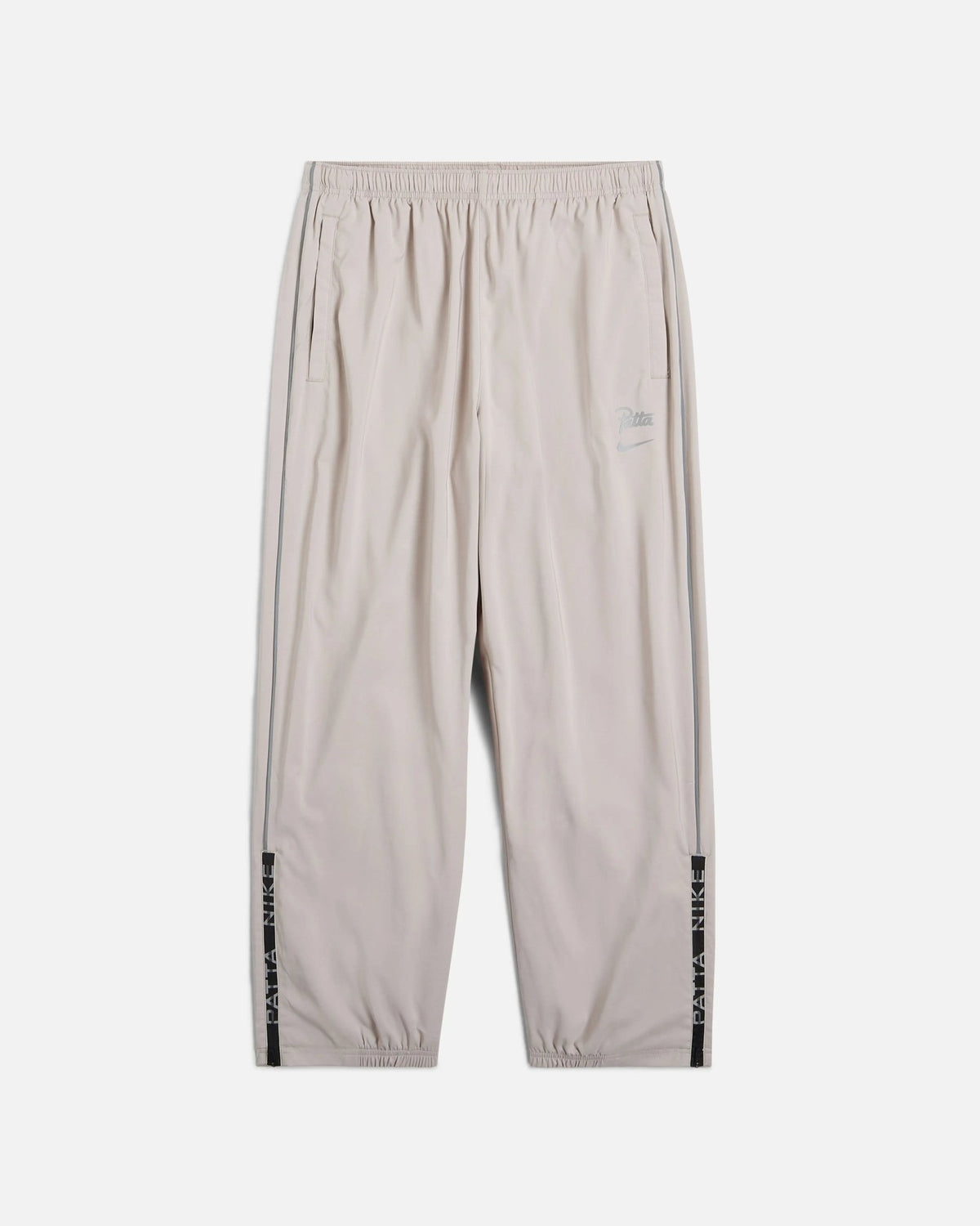 Front view of Nike x Patta Running Team track pants in Sanddrift cream with reflective piping.