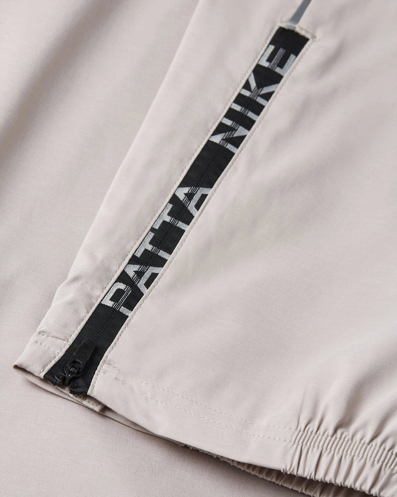 Close-up of the branded leg zipper and elastic cuff on Nike x Patta Sanddrift cream track pants.