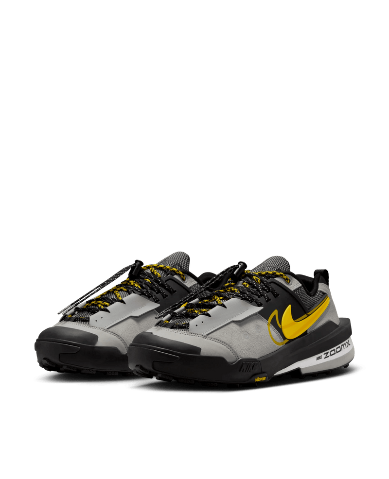Nike Zegamadome x Sacai sneakers in matte silver and black with yellow Swoosh accents.