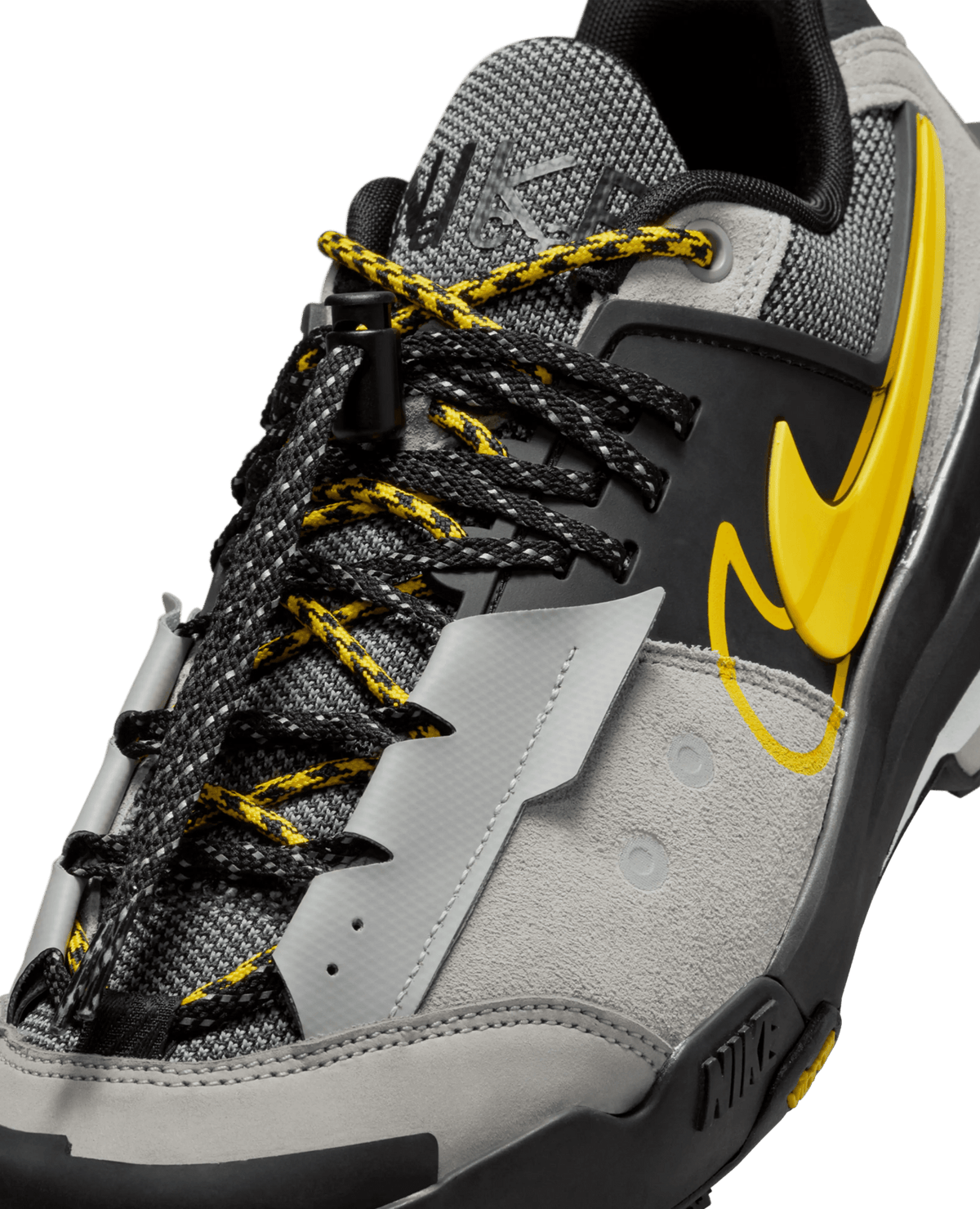Close-up of Nike Zegamadome x Sacai sneaker featuring double laces, matte silver suede overlays, and yellow accents.