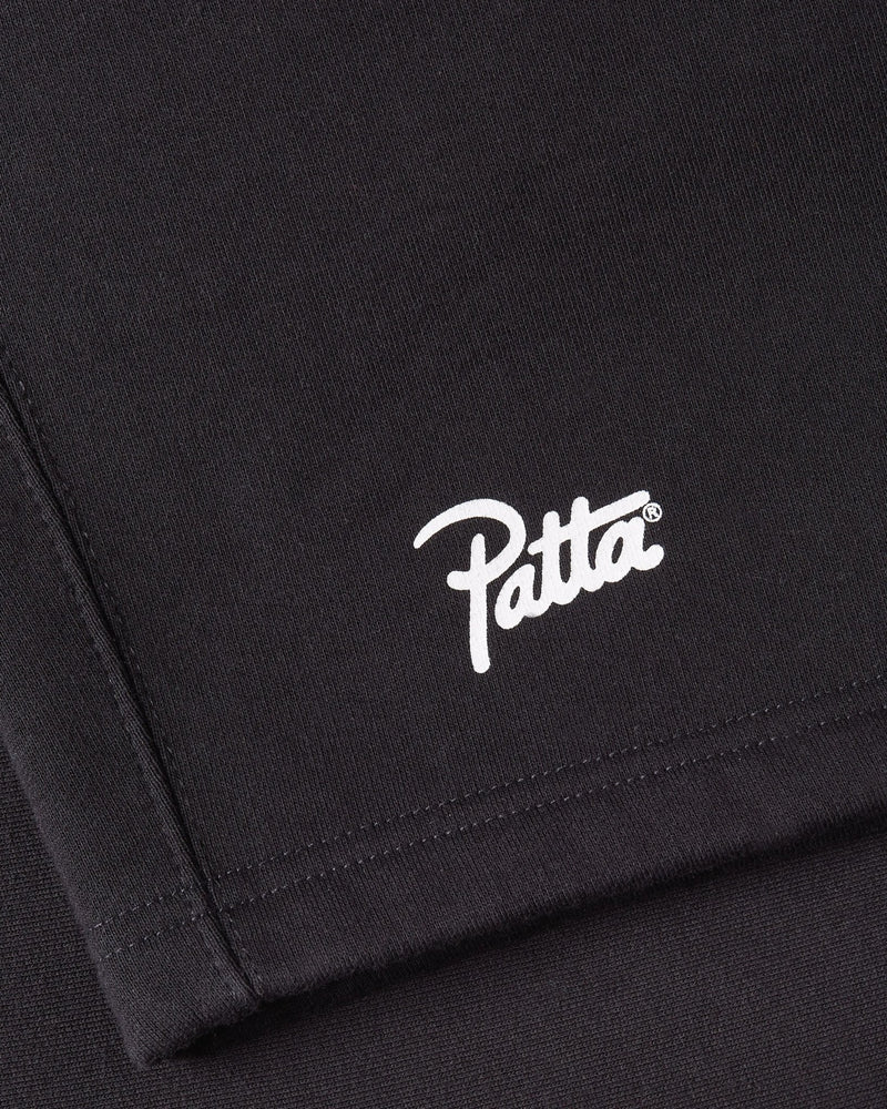 Close-up of the white Patta script logo printed on black Classic Jogging Shorts.