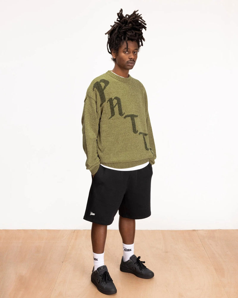 Model wearing black Patta Classic Jogging Shorts paired with an olive green knit sweater.