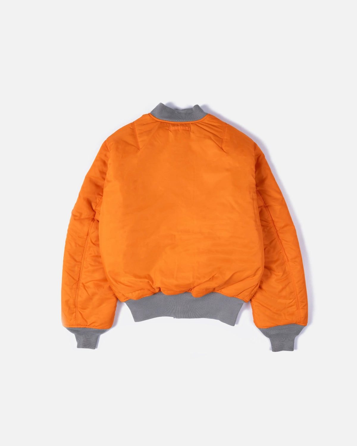 Back view of the reversible orange Patta x Alpha Industries MA-1 bomber jacket with grey ribbed trim.