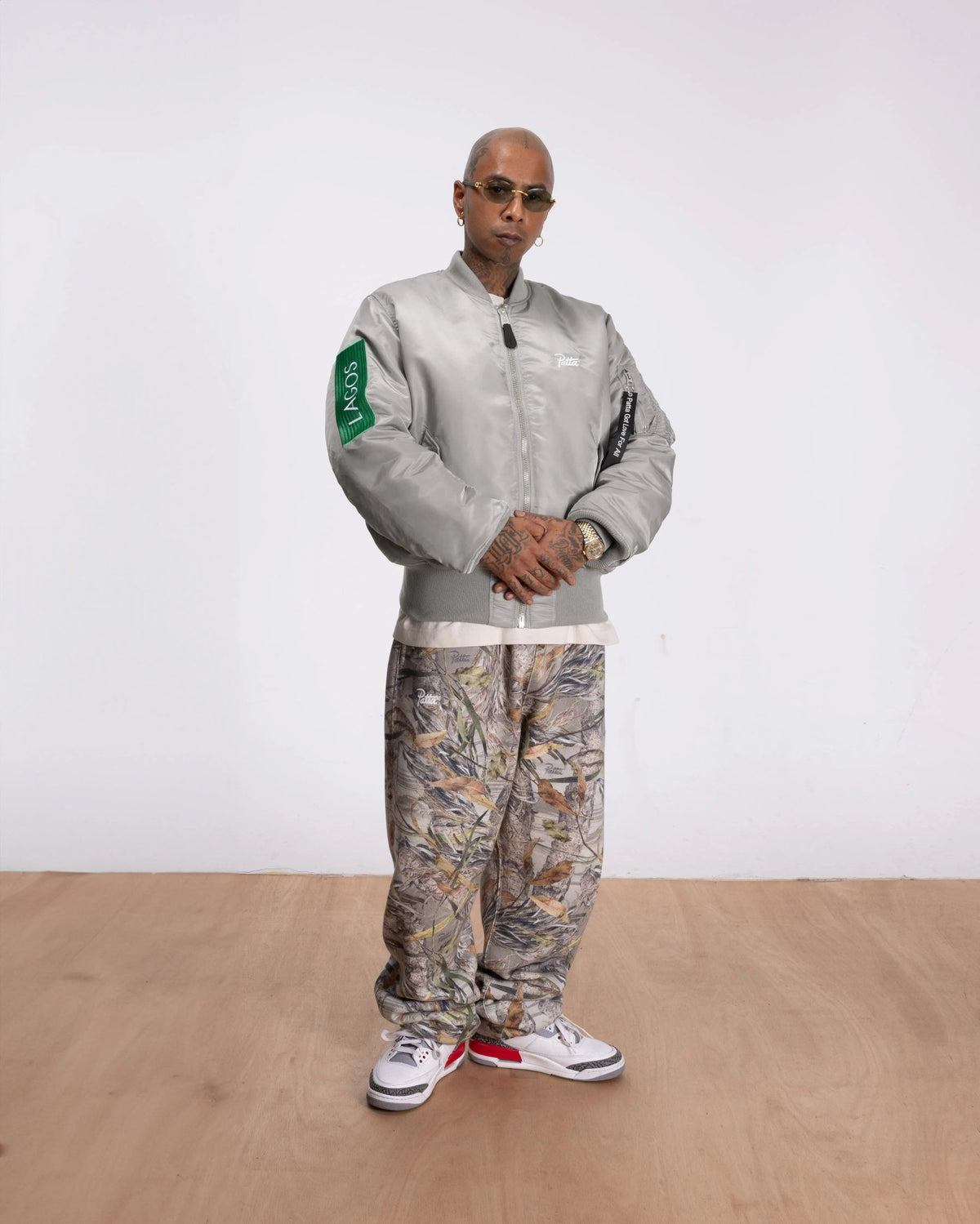 Model wearing the silver Patta x Alpha Industries MA-1 Celebration Bomber Jacket with green Lagos patch.