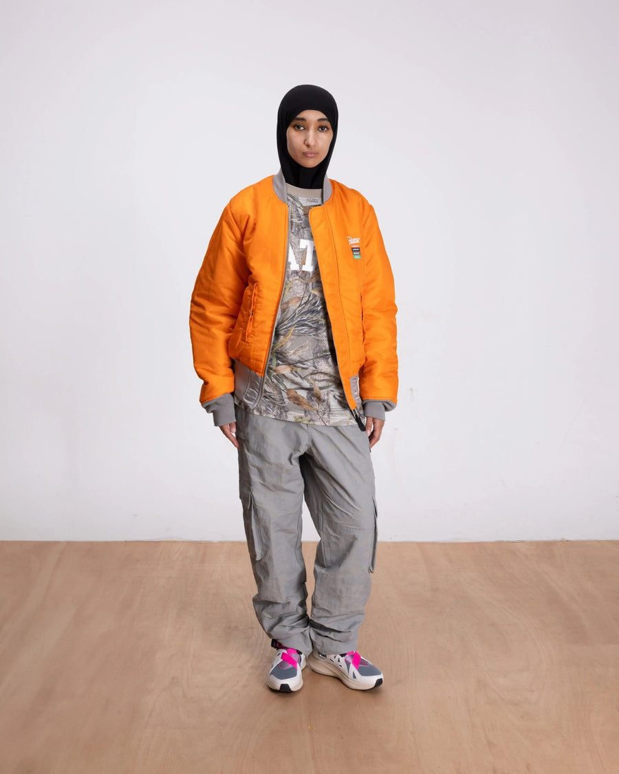 Model wearing the reversible orange side of the Patta x Alpha Industries MA-1 bomber jacket.