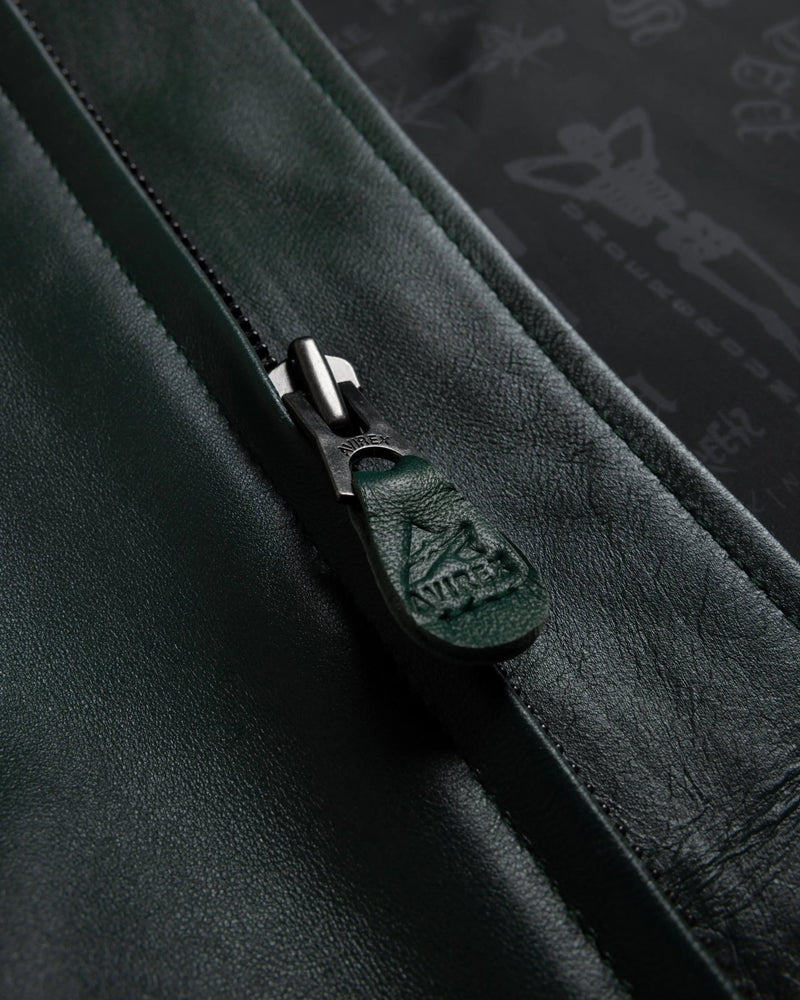 Close-up of the green leather zipper pull with embossed Avirex logo on the Patta x Avirex Icon Jacket.