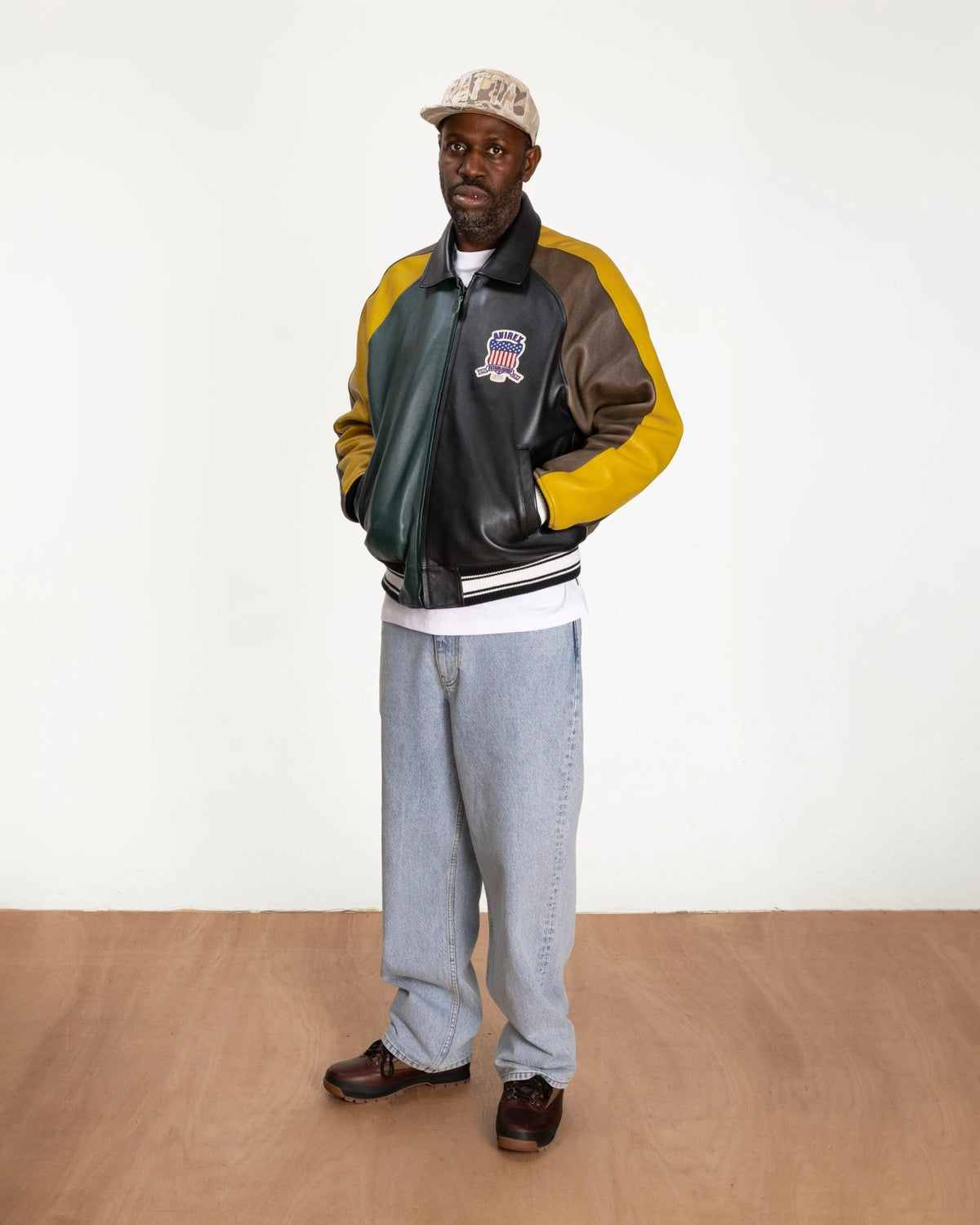 Model wearing the multicolor Patta x Avirex Icon leather jacket in a studio setting.