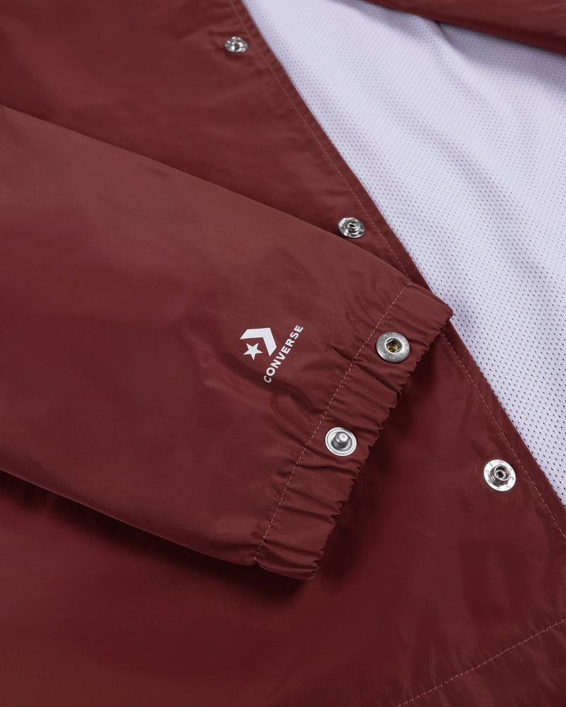 Close-up of the garnet Patta x Converse Coaches Jacket sleeve cuff with snap buttons and printed logo.