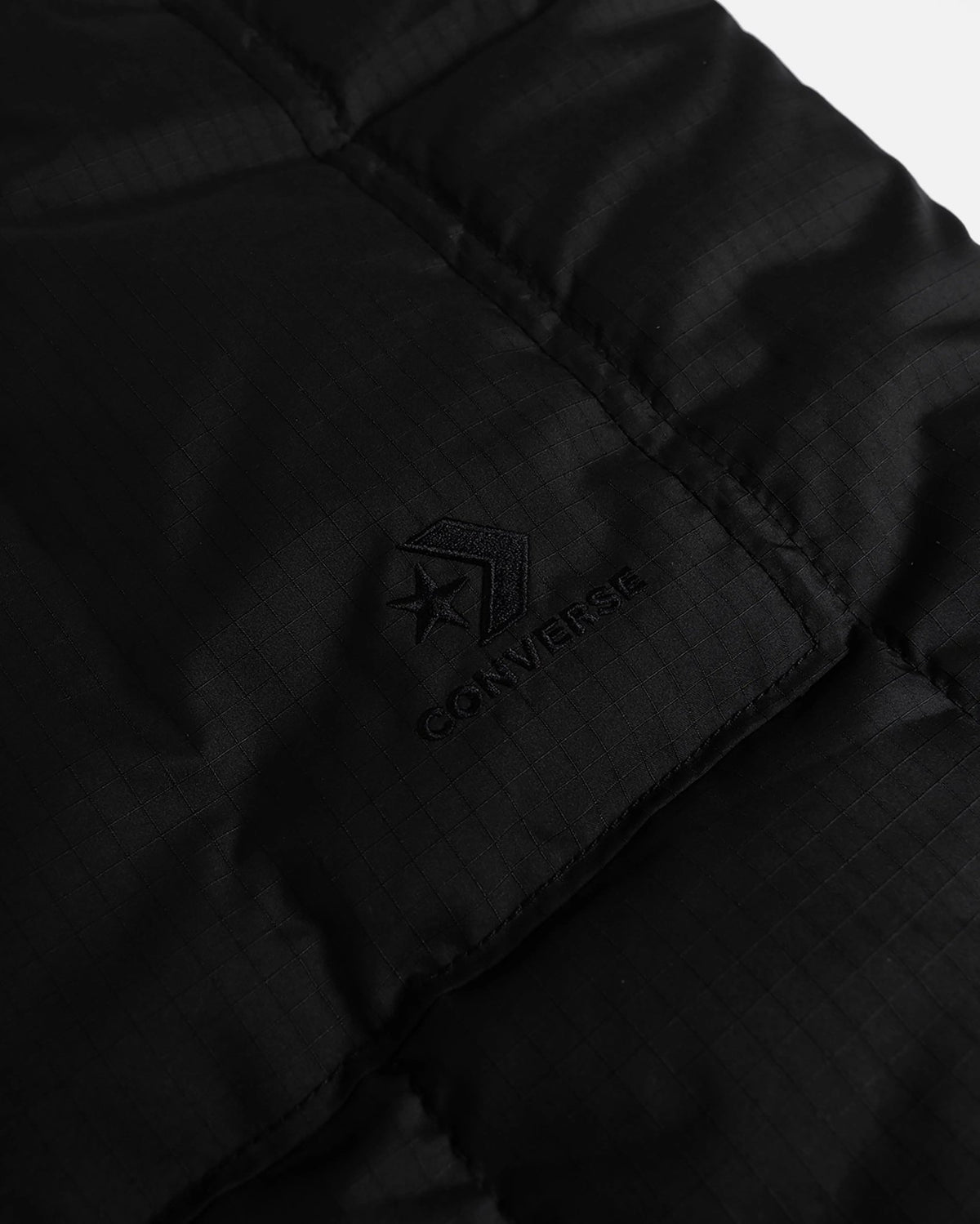 Detail of embroidered Converse Star Chevron logo on the black quilted side of Patta reversible vest.