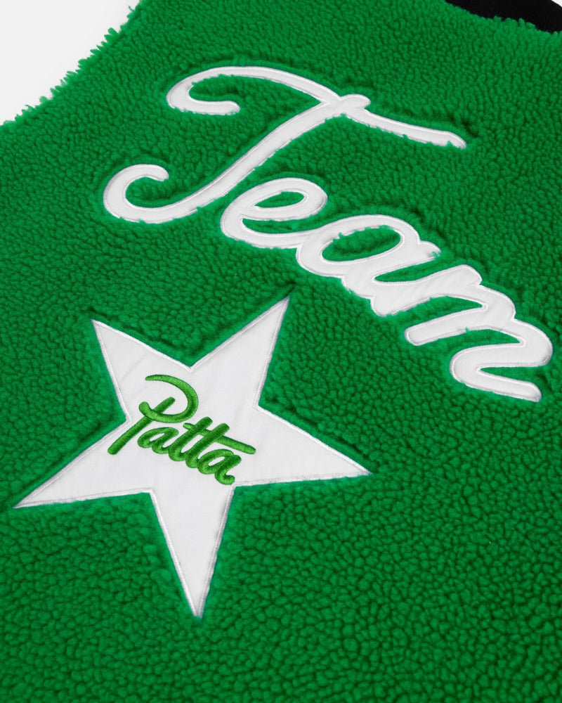 Close-up of green fleece on the Patta x Converse Reversible Vest with embroidered Team text and star patch.