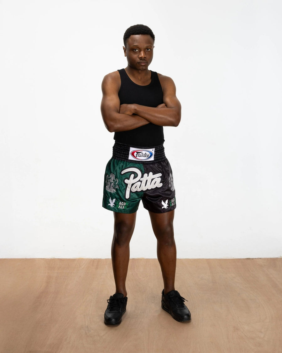 Model wearing green and black Patta x Fairtex satin Muay Thai shorts with embroidered logos.