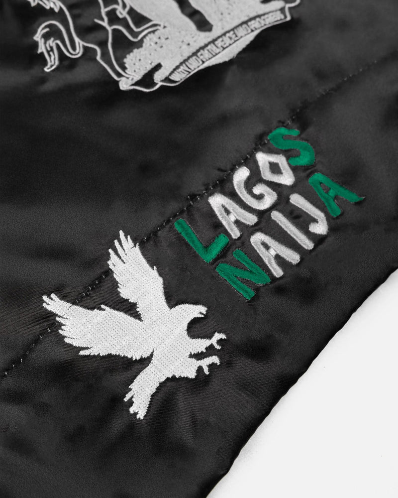 Close-up of embroidered Lagos Naija lettering and eagle on black satin Patta x Fairtex Muay Thai shorts.