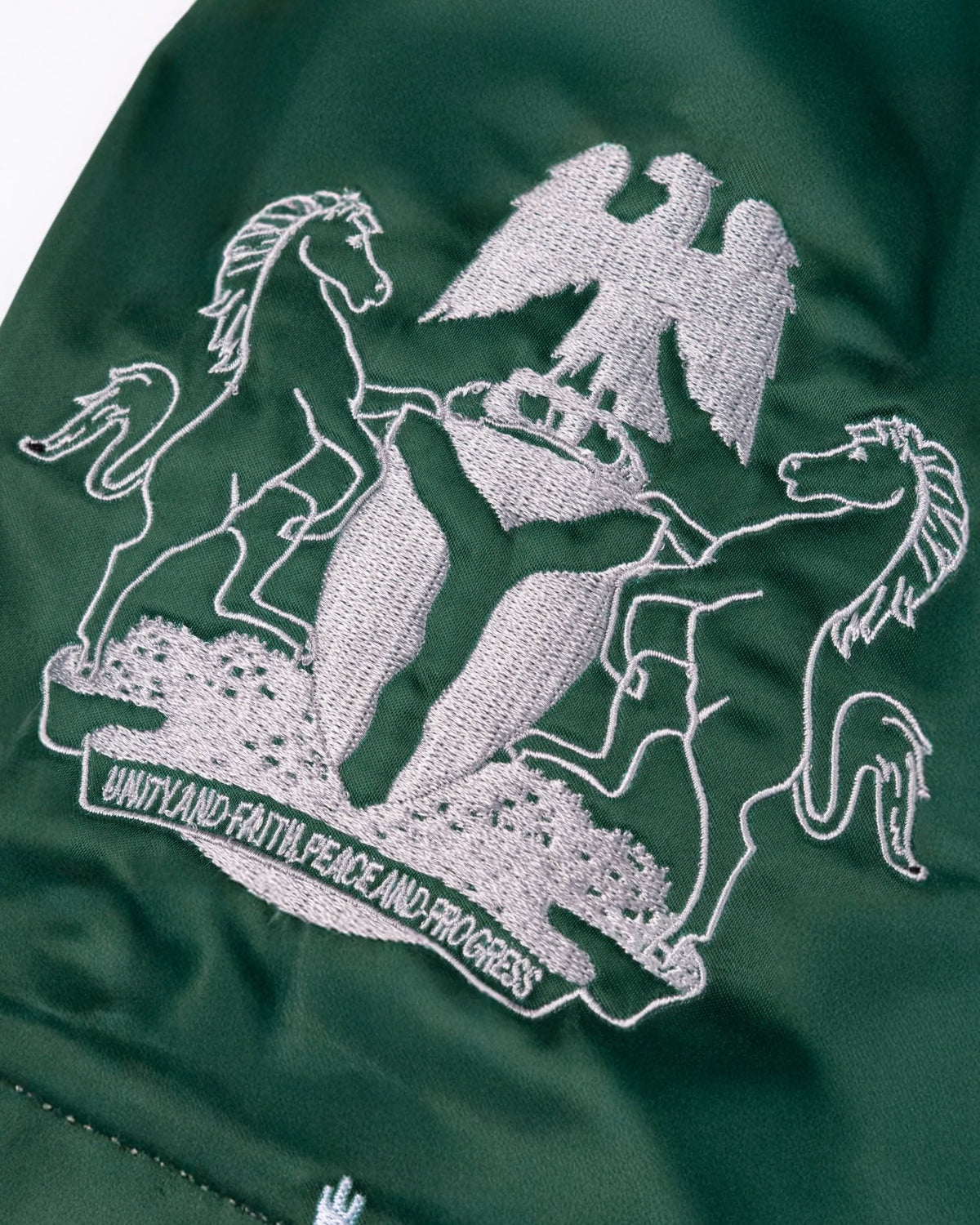 Embroidered Nigerian coat of arms on green satin Patta x Fairtex Muay Thai shorts.