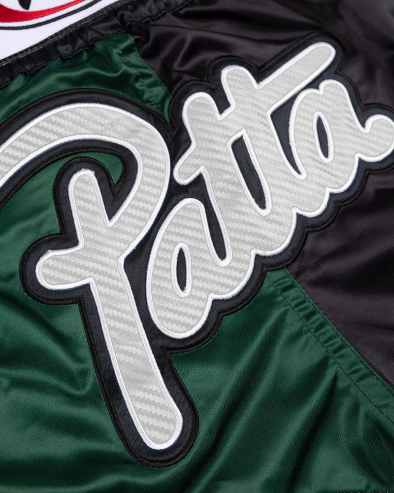 Close-up of the white Patta script patch on green and black satin Muay Thai shorts.