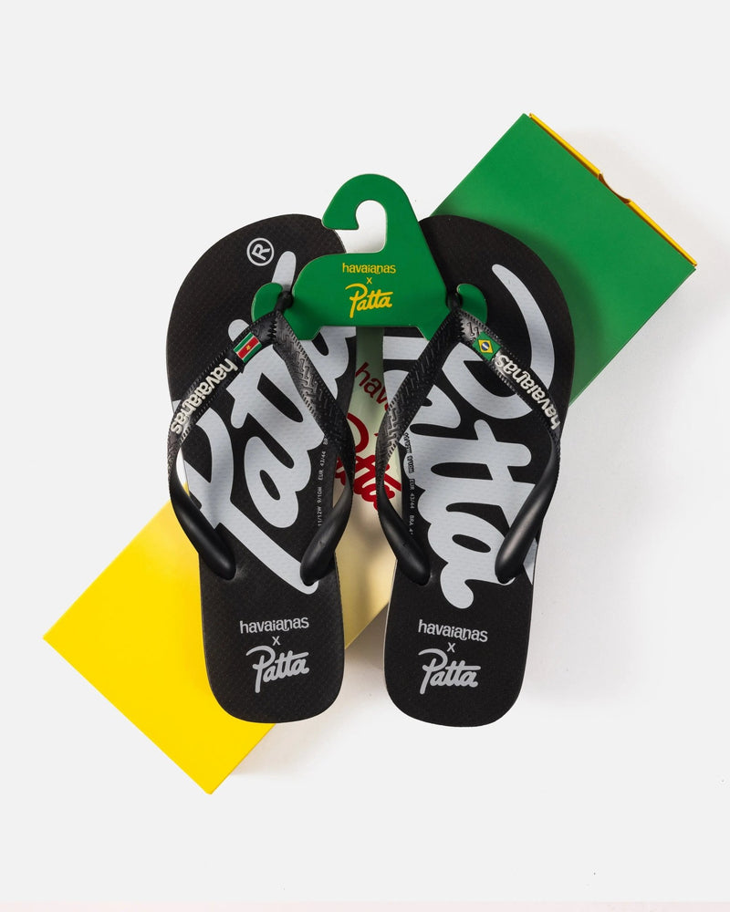 Black Patta x Havaianas flip-flops with white script logos resting on a green and yellow box.