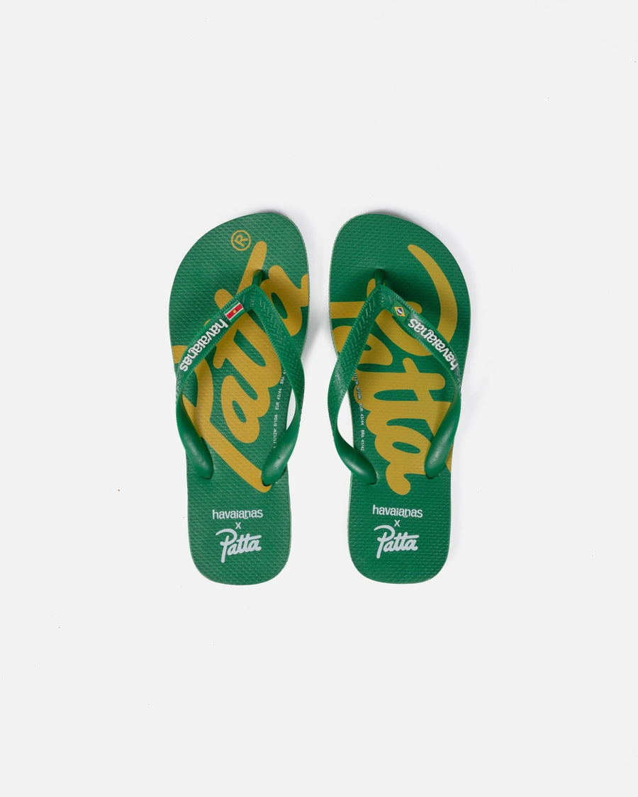 Green and yellow Patta x Havaianas flip-flops with printed logo footbeds on a white background.