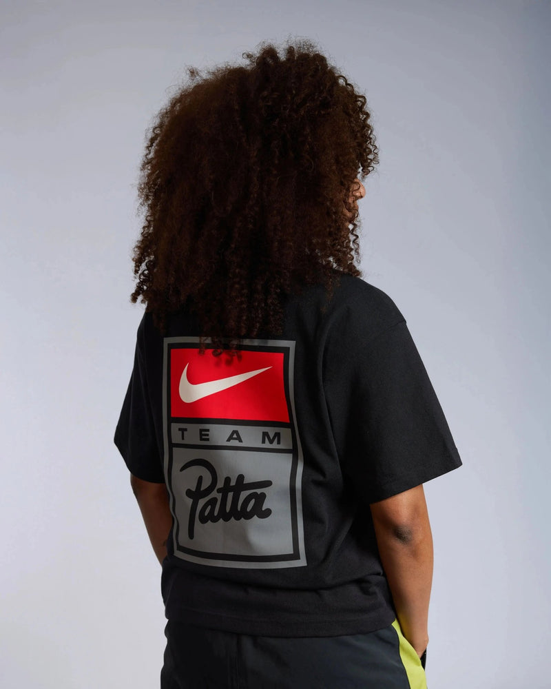 Model wearing the black Patta x Nike NRG T-shirt with a large Team Patta logo badge printed on the back.