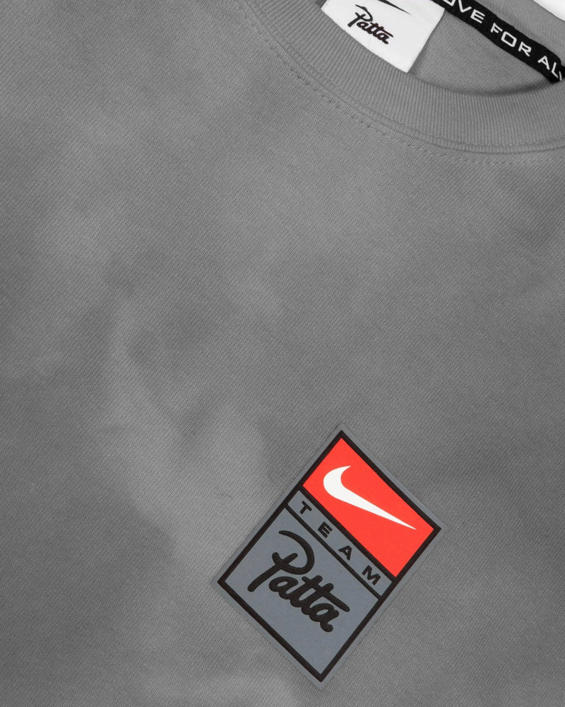 Close-up of grey washed Patta x Nike NRG T-shirt with silicone Team Patta chest logo badge.