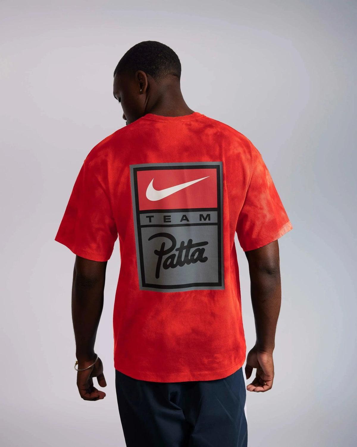 Back view of a model wearing the red washed Patta x Nike NRG T-shirt with large back graphic.