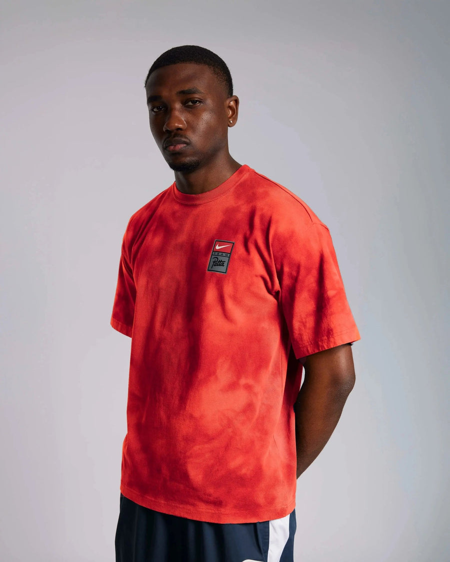 Model wearing the Patta x Nike NRG washed red tie-dye T-shirt with chest logo.